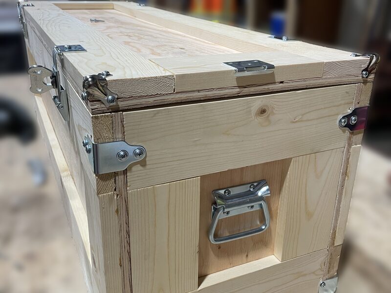 A finished wooden crate with steel corner brackets, latches and a carry handle.